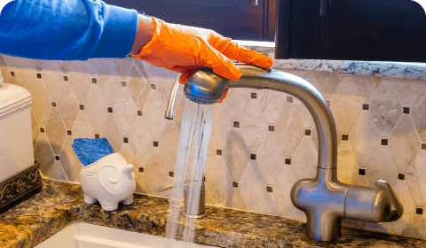 Water running from a kitchen faucet into a measuring jug during a flow check